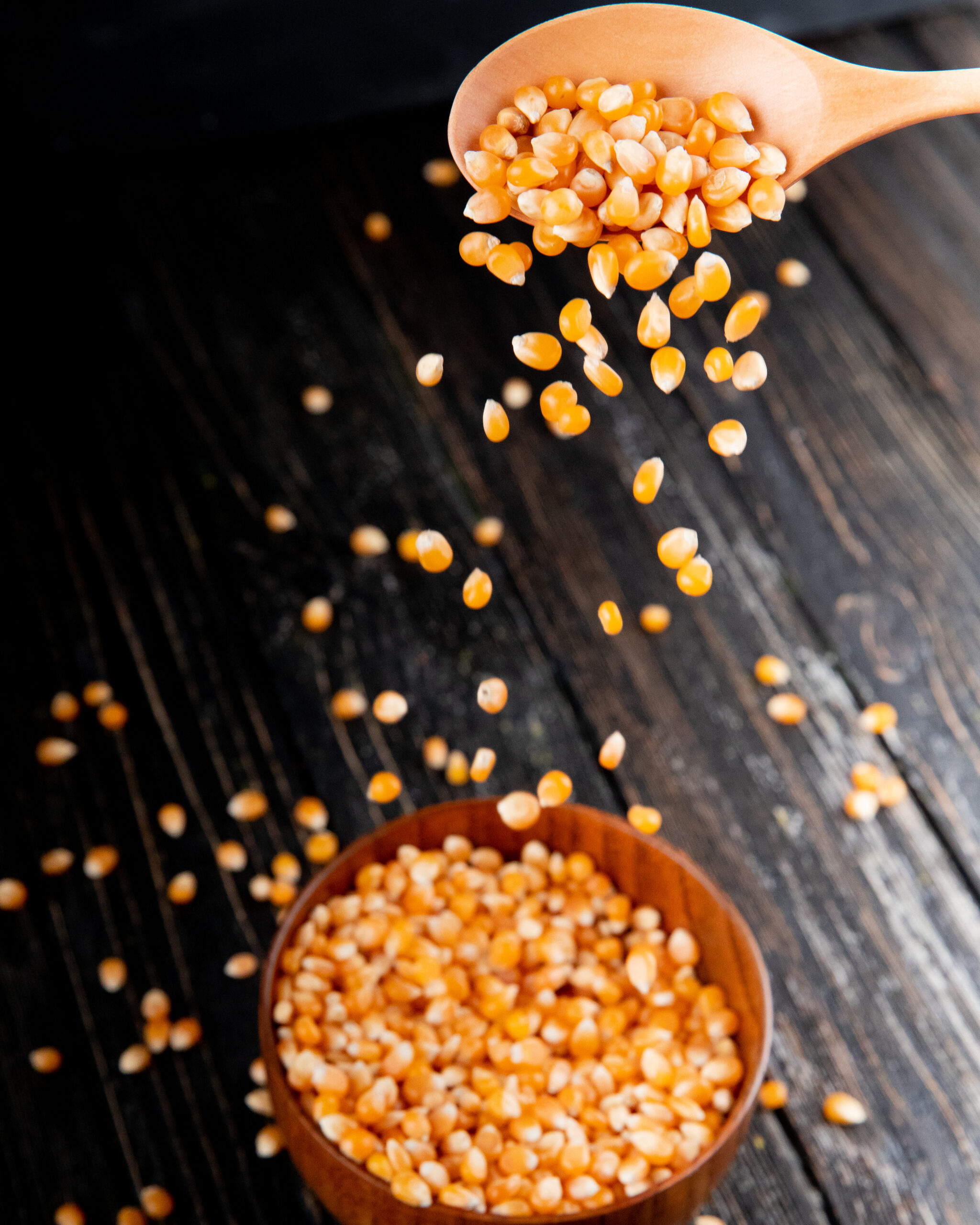 front view corn pour from a wooden spoon into a bowl